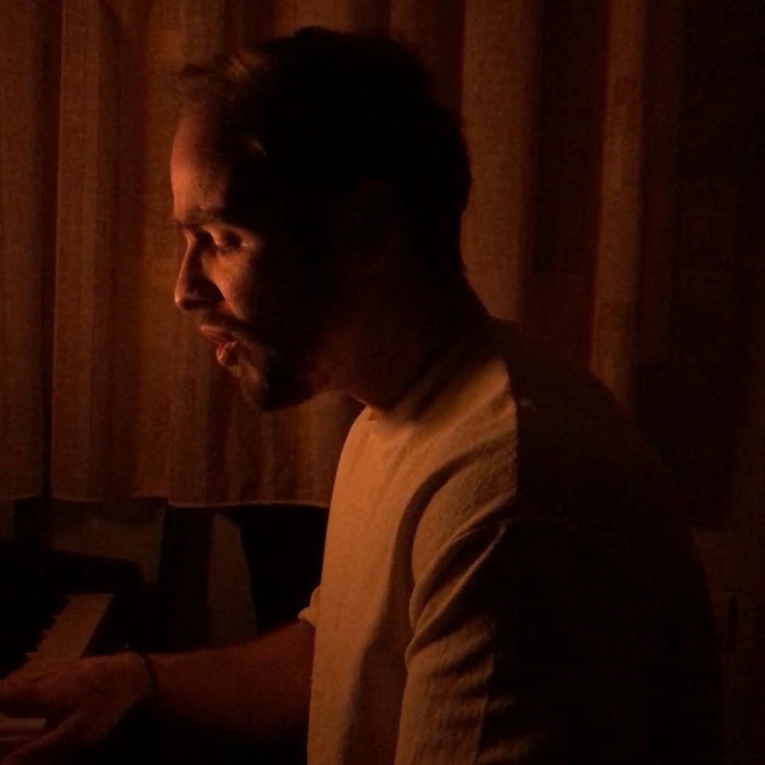 Giannis Zachos singing and playing piano in warm light